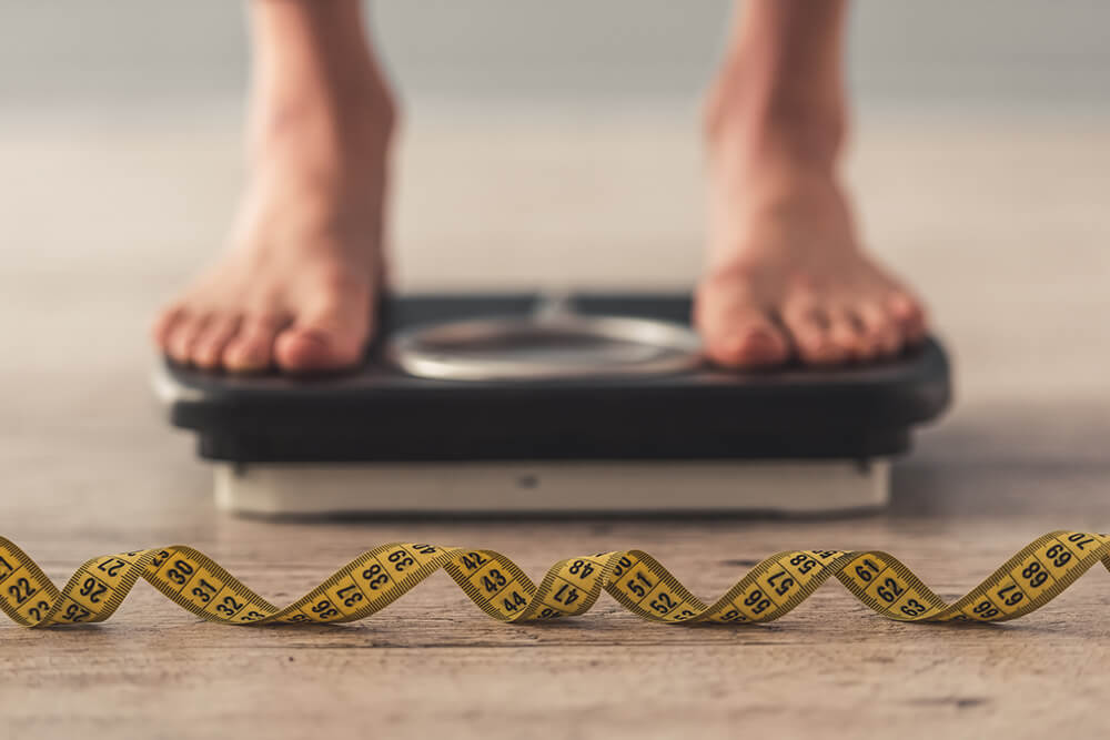 Weight-Loss-Services-2 person stepping on a weighing scale