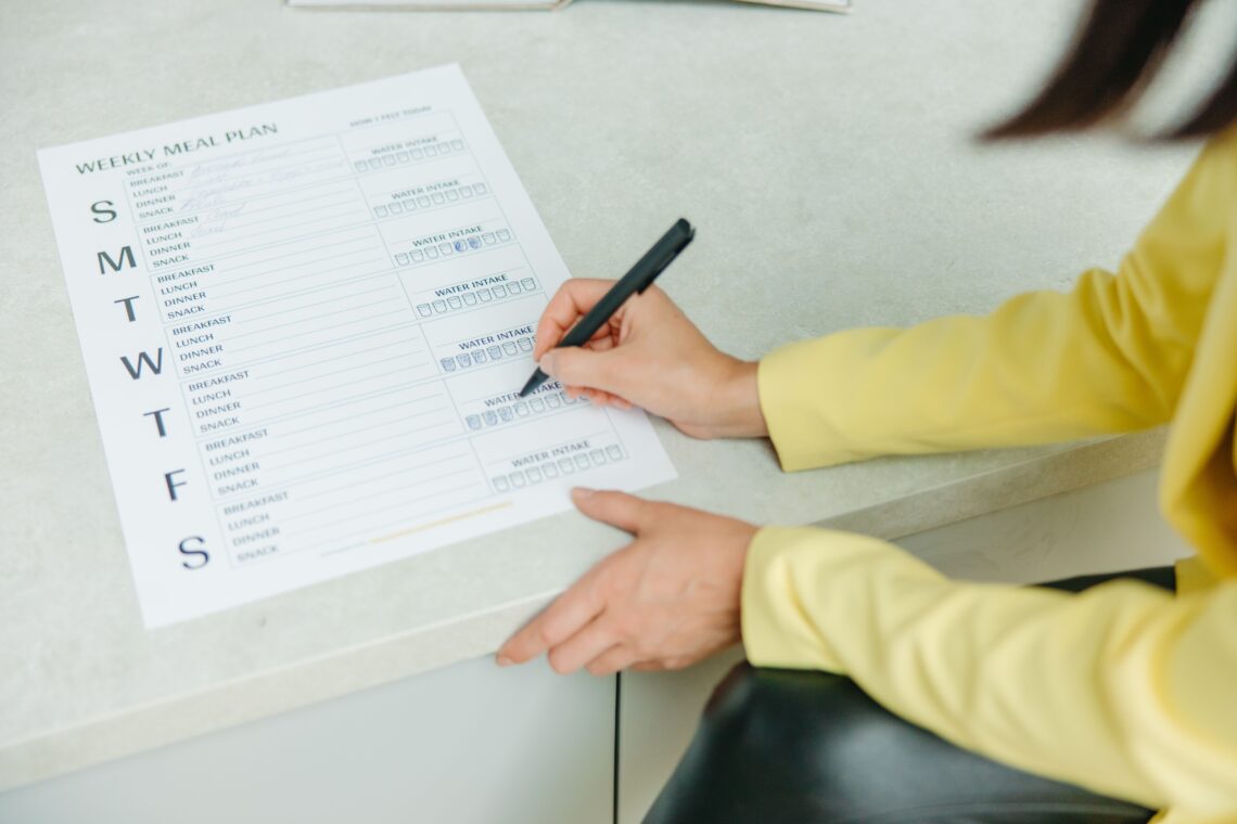 Person completing a weekly meal plan and water intake tracker as part of a structured GLP-1 weight loss program in Utah